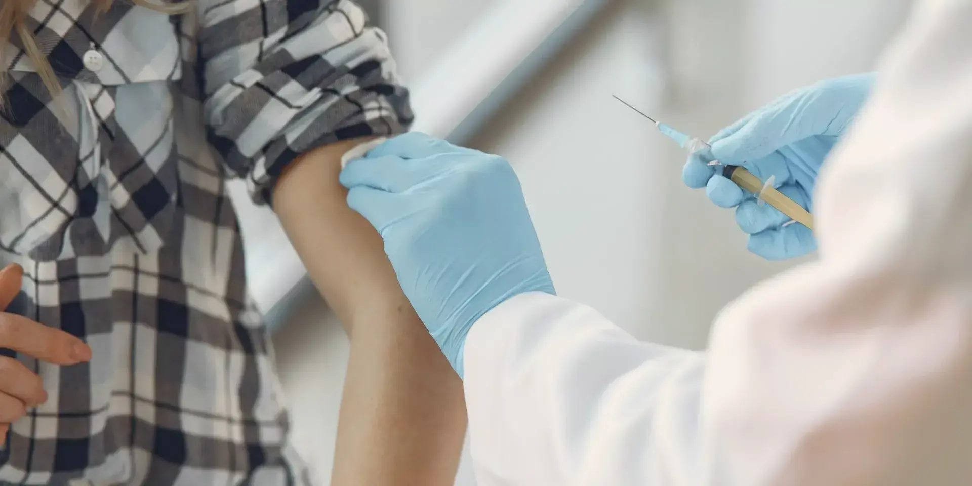 a man with his sleeve rolled up about to receive a vaccination from a doctor