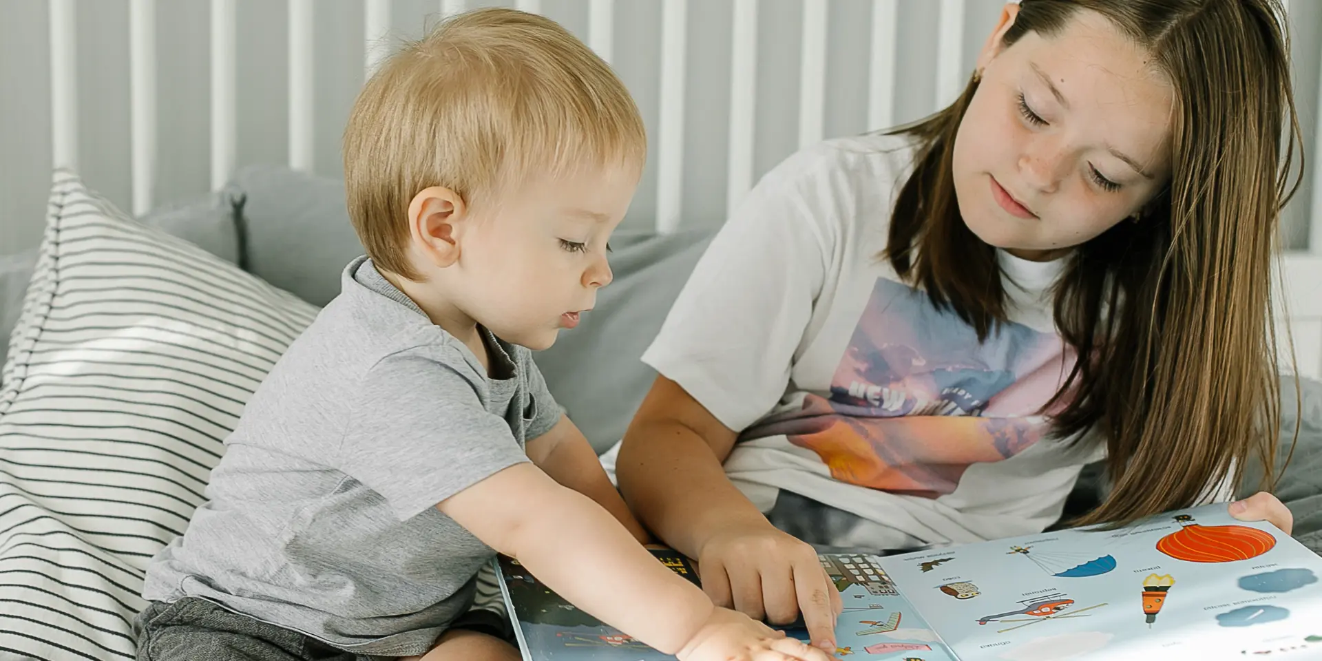 Sisters and brother reading books in light bedroom at home Concept of kids education development