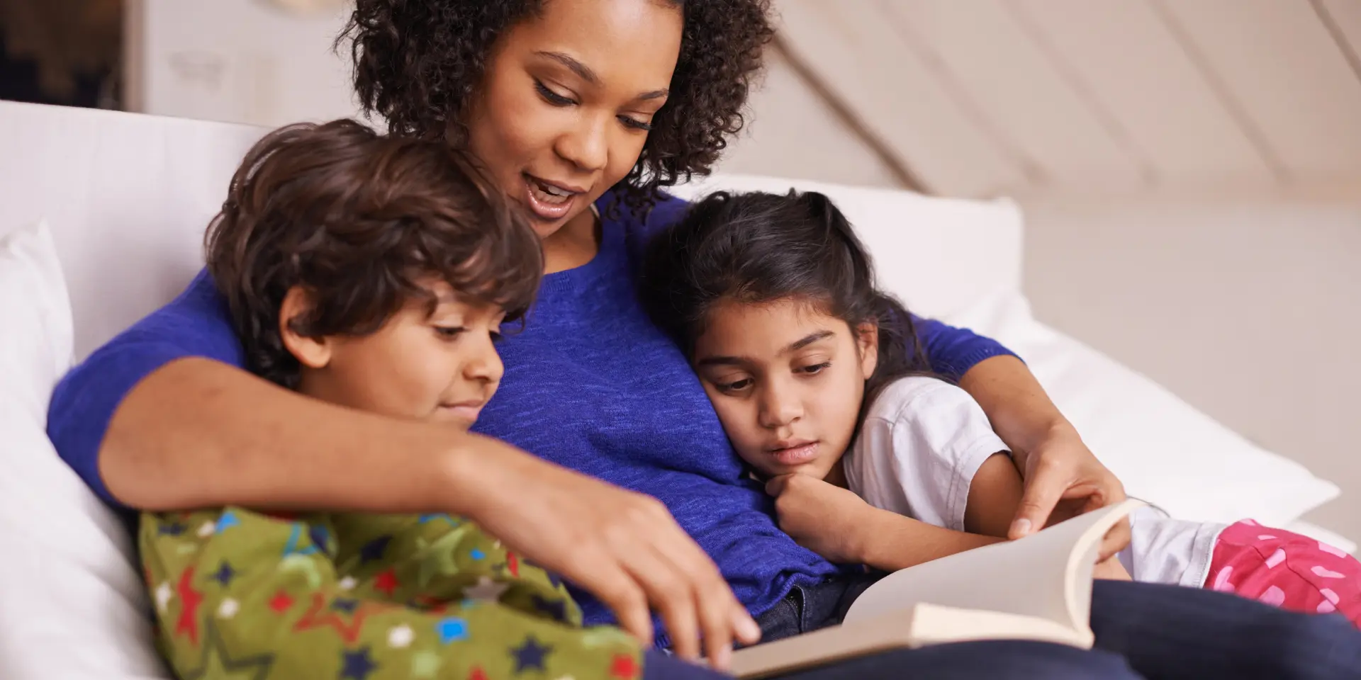 A young mother reading to her children while relaxing at home