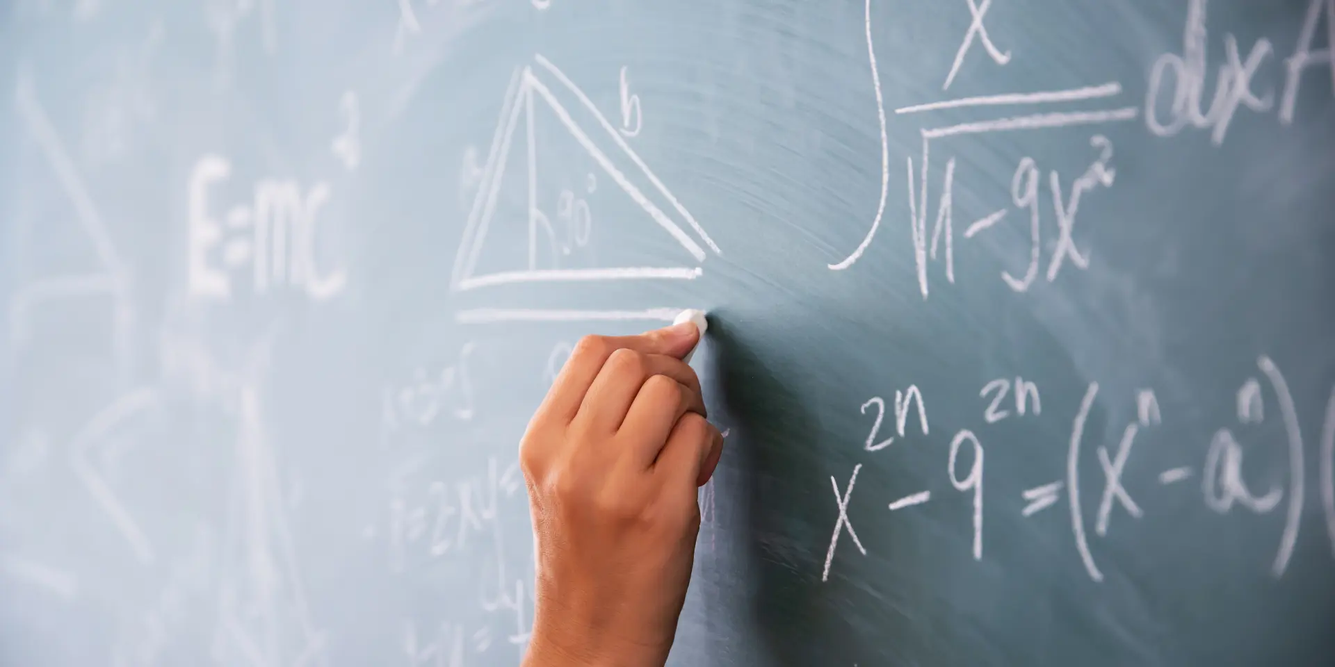 Teacher or student writing on blackboard during math lesson in school classroom