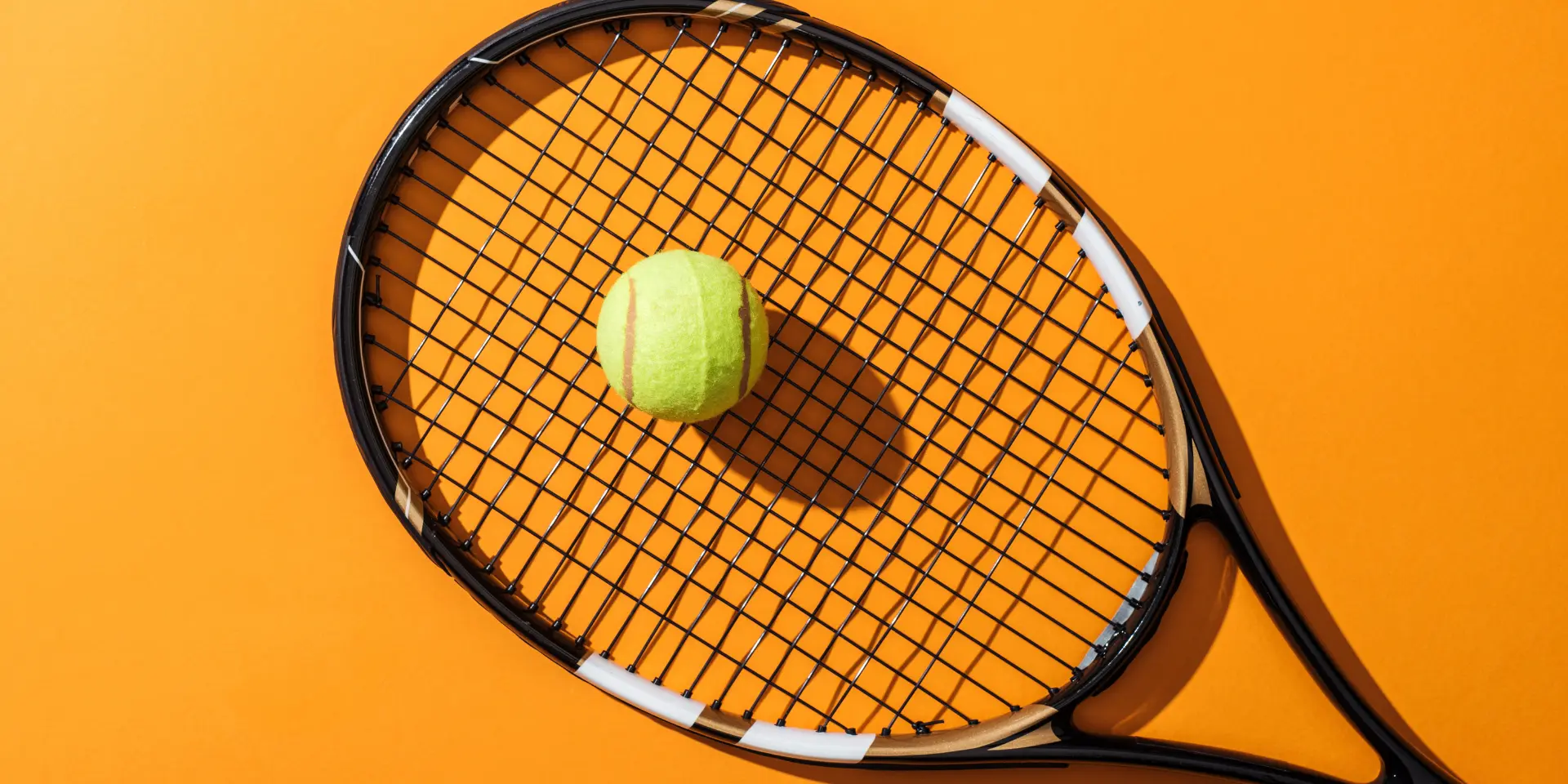 Top view of tennis racket near green tennis ball on yellow