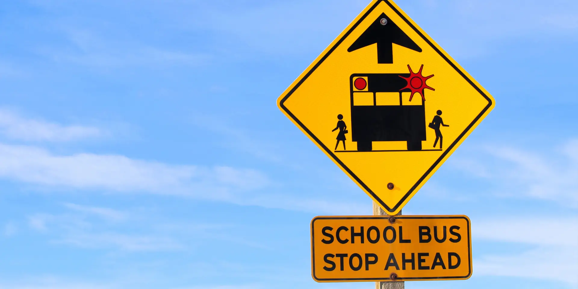 Closeup of a School Bus Stop Ahead Sign Against a Blue Sky