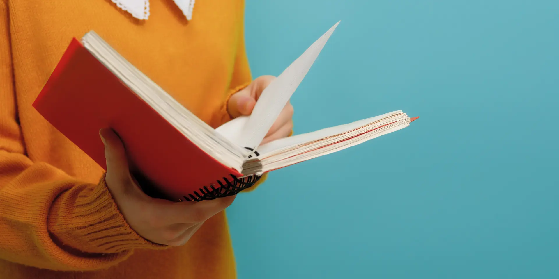 Girl with book on background of bright teal wall