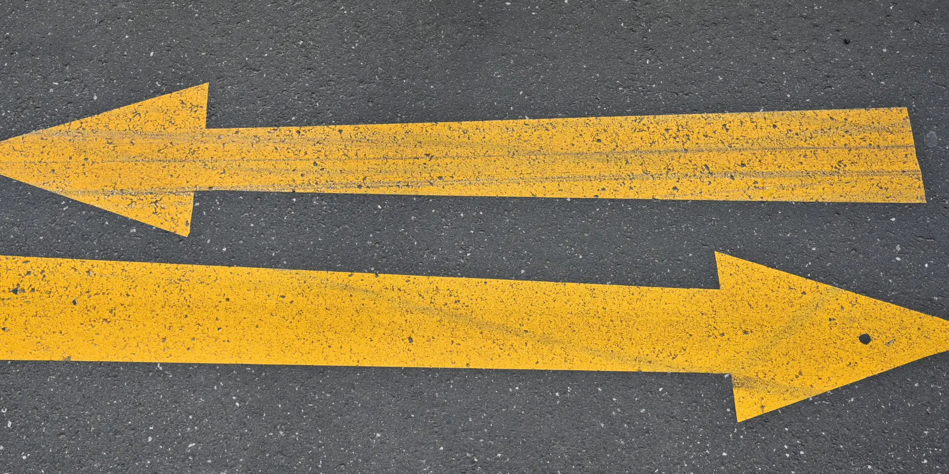 Closeup shot of yellow opposite direction signs on asphalt