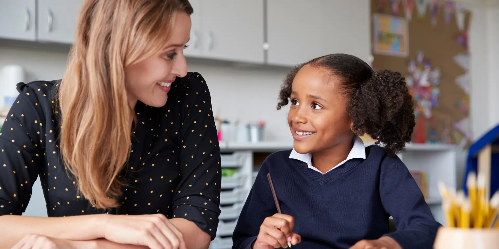 Young female primary school teacher working one on one with a schoolgirl at a table