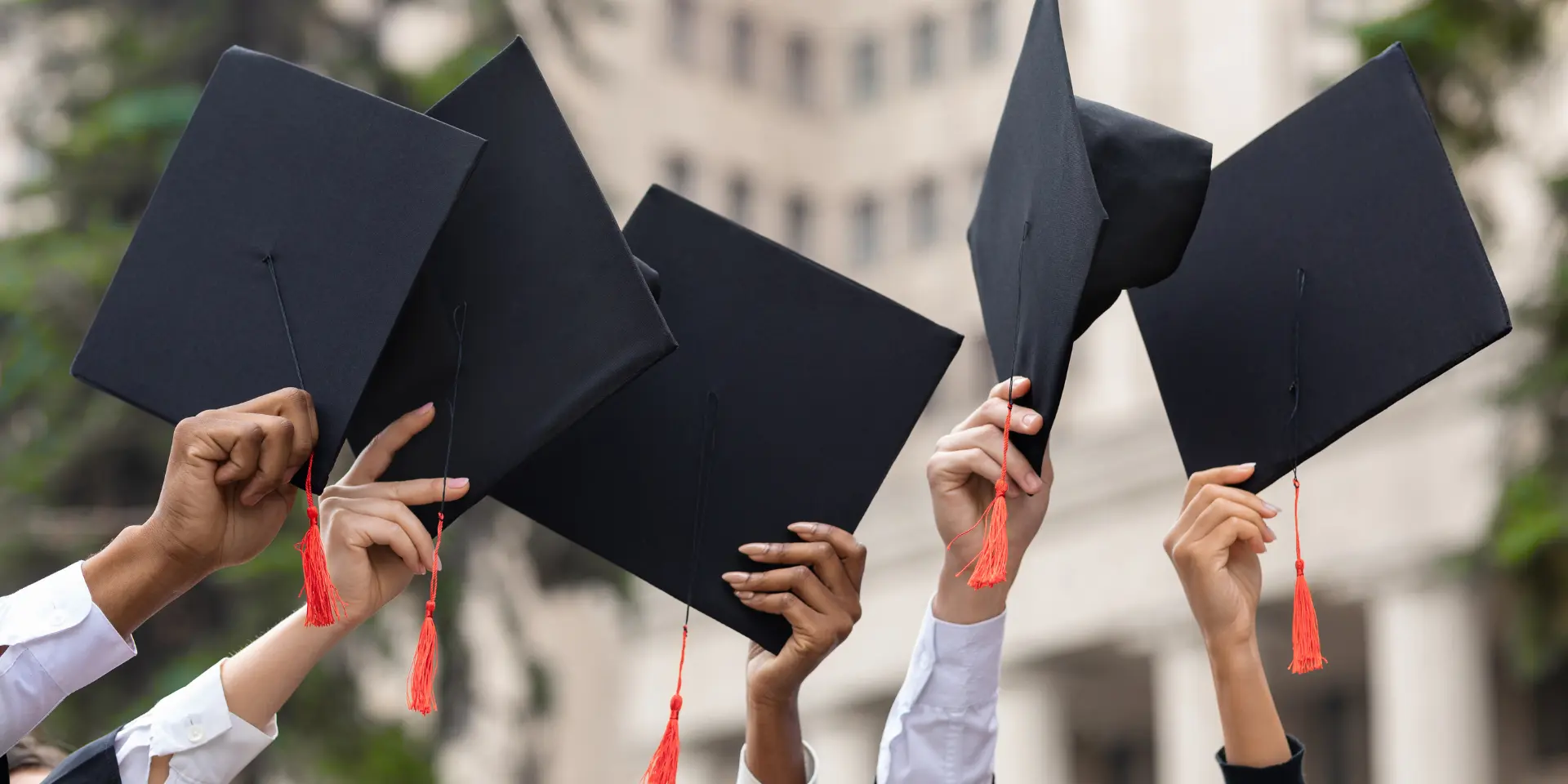 Cropped of students raising up hands with caps