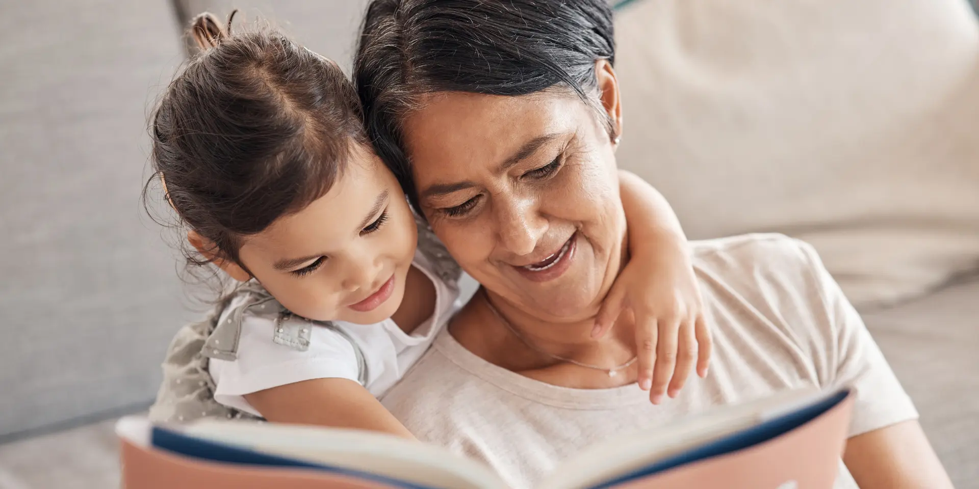 Education learning and girl and grandmother reading a book on a sofa relax and bonding in living