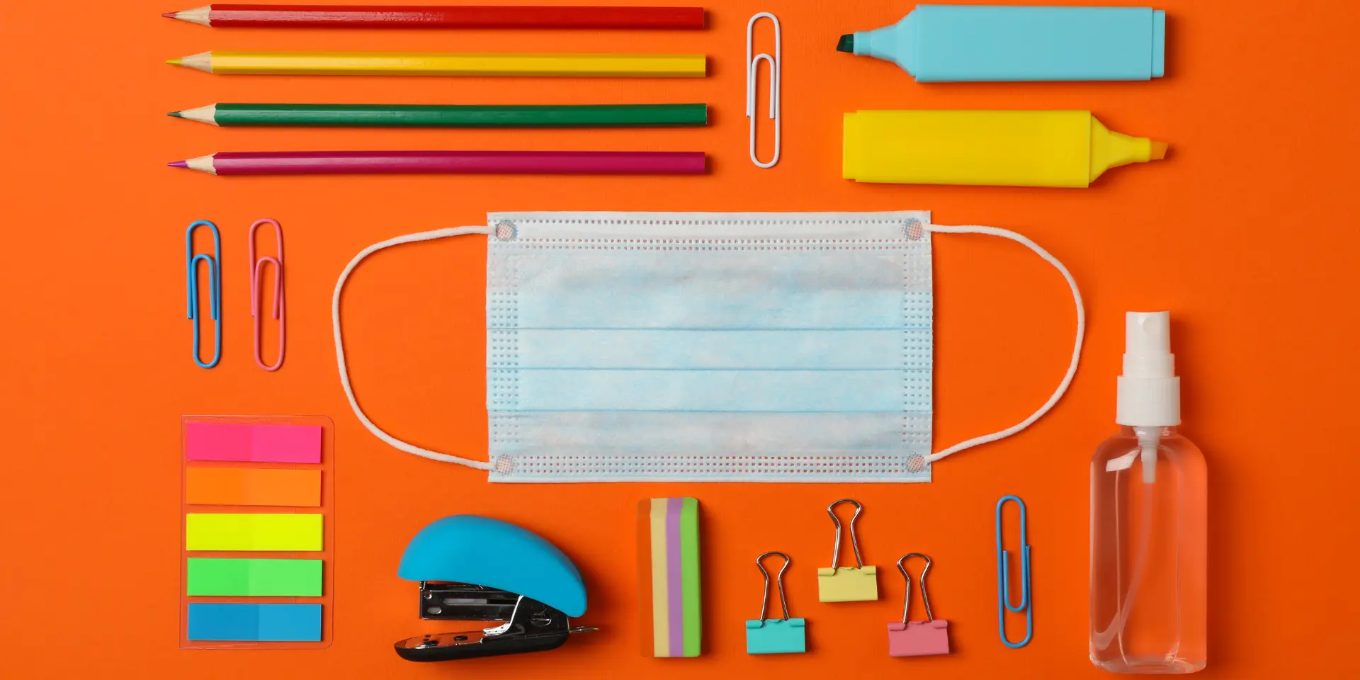 Flat lay with school supplies medical mask and sanitizer on orange background