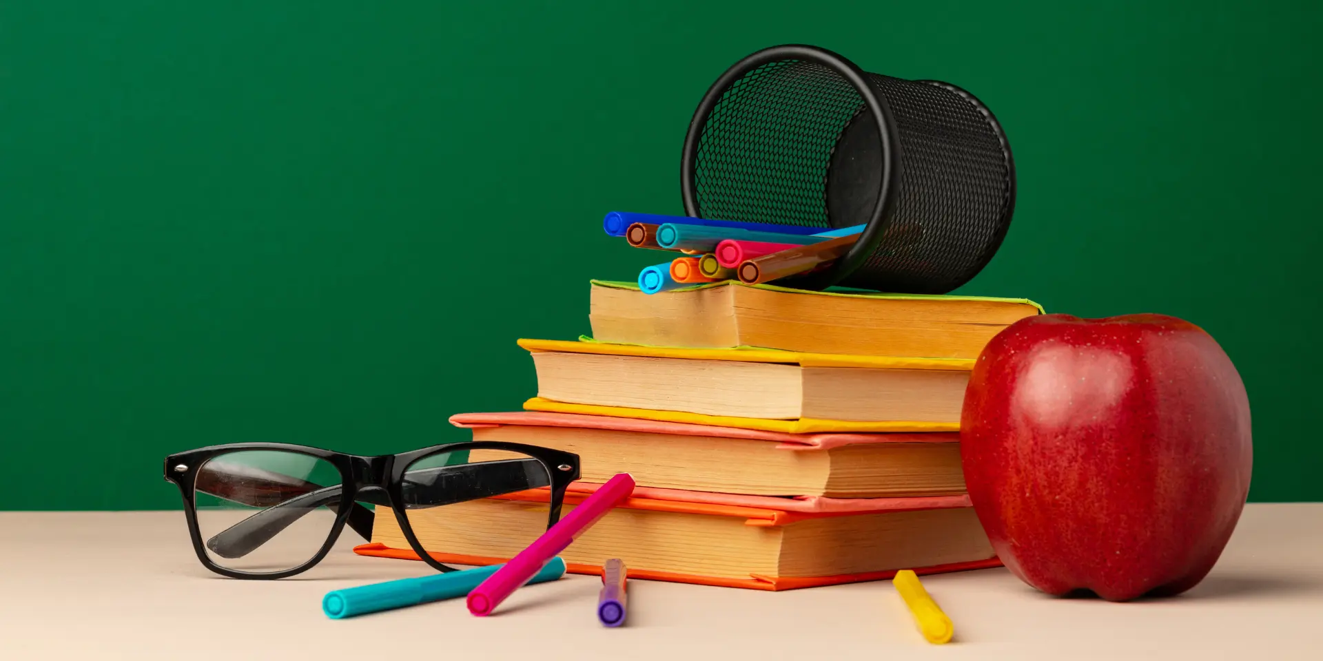 Pile of books and red apple on desk