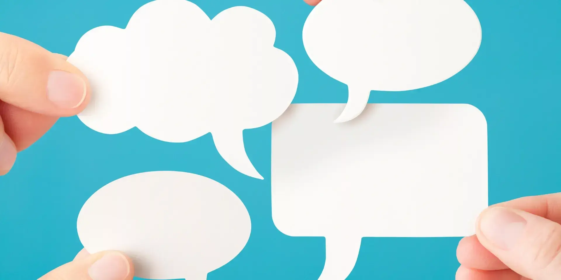 hands holding paper speech bubbles against a blue background