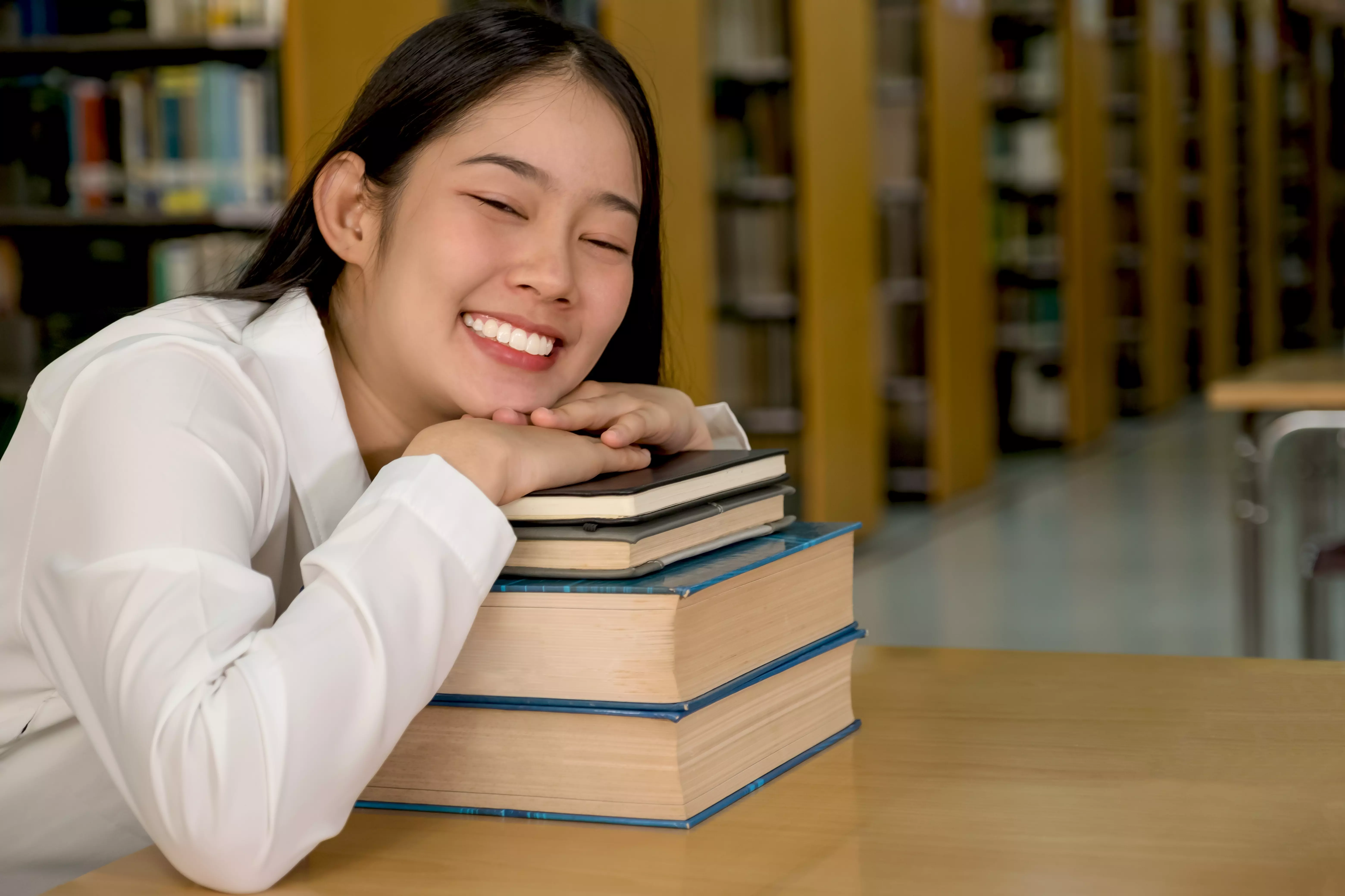 Infographic of an Asian female college student lying on a set of books.