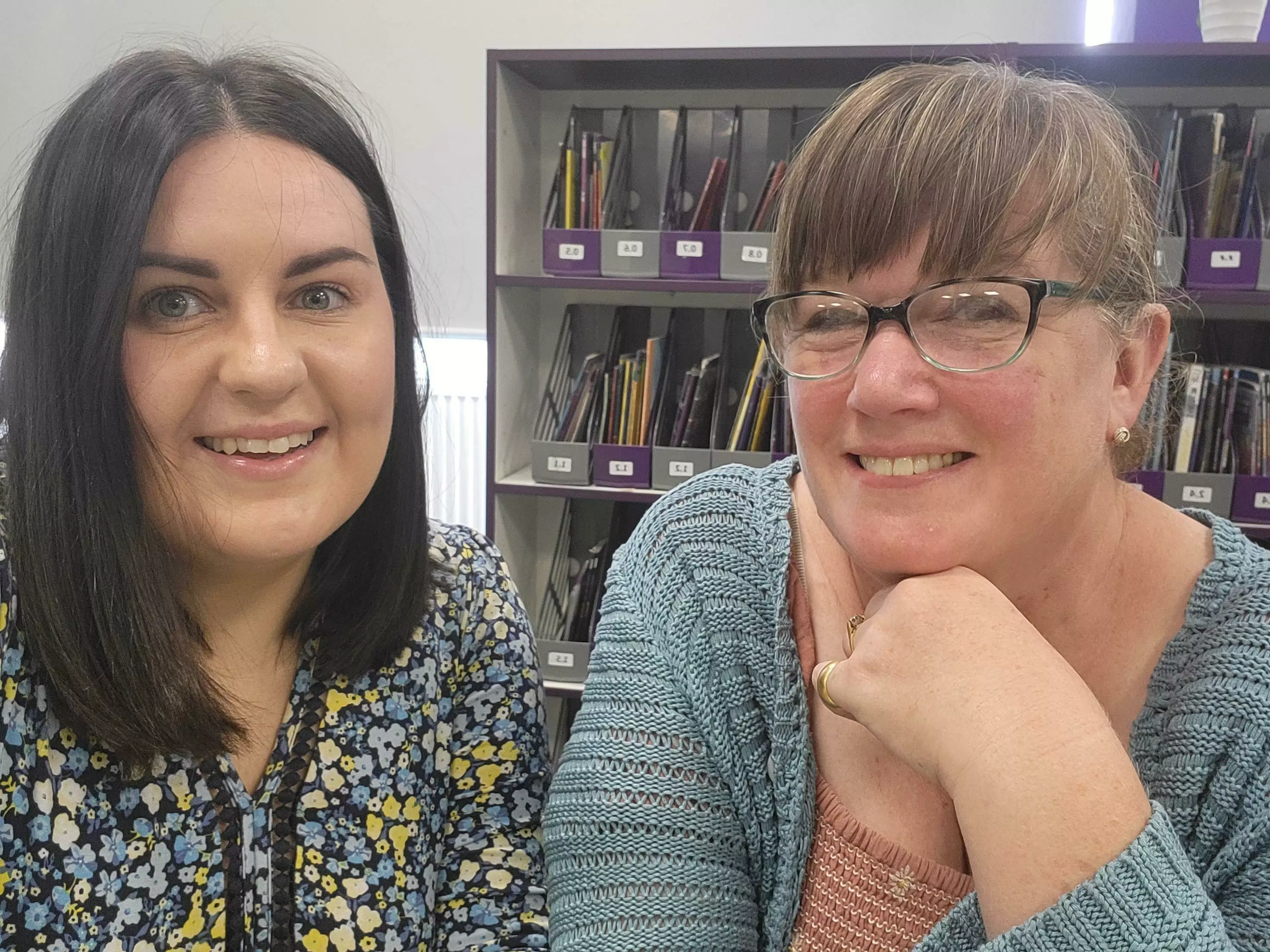 two educators from the john frost school sat in a library smiling at the camera