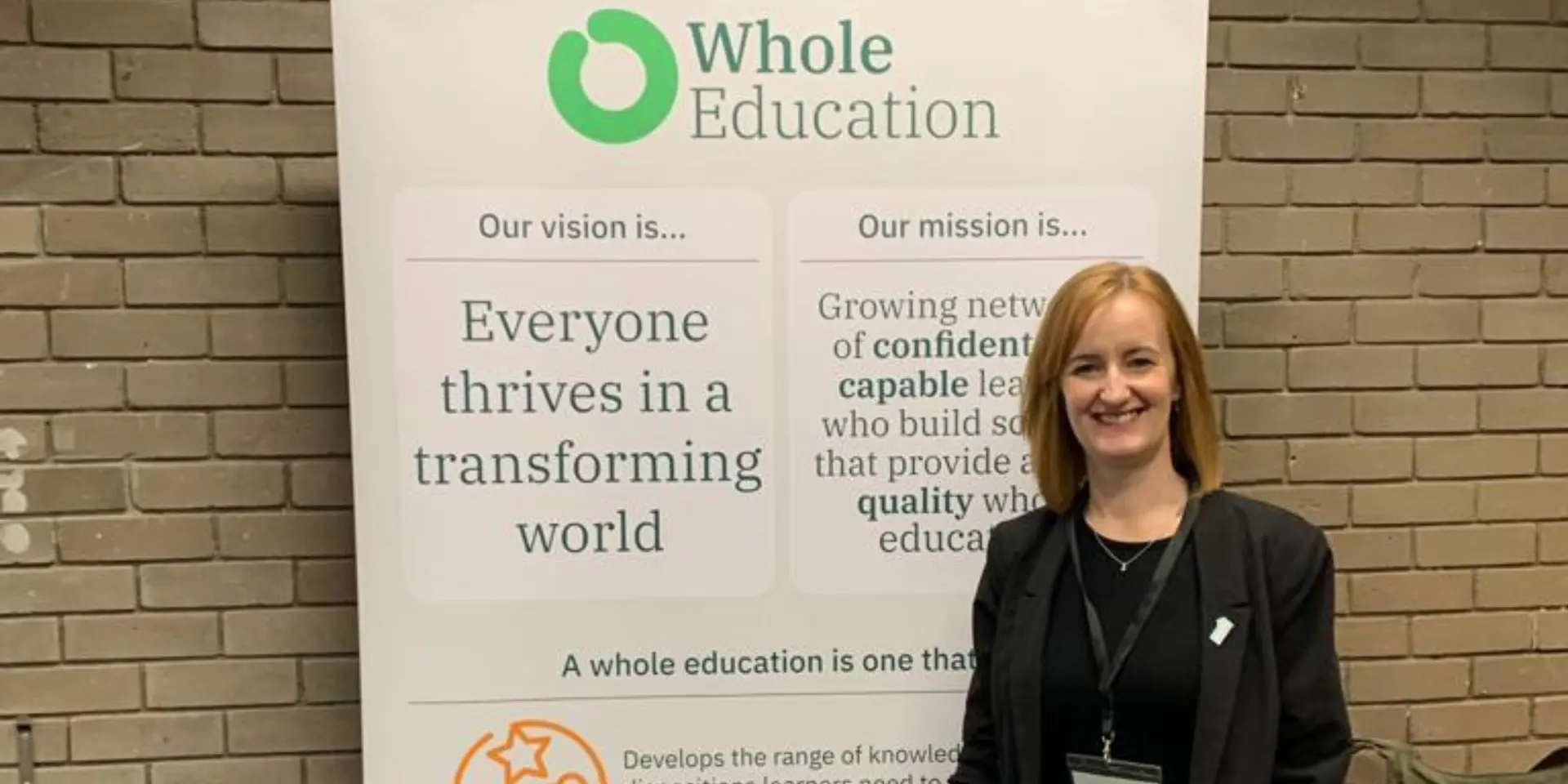 Lexonik CEO Sarah Ledger stood in front of a banner at the Whole Education conference