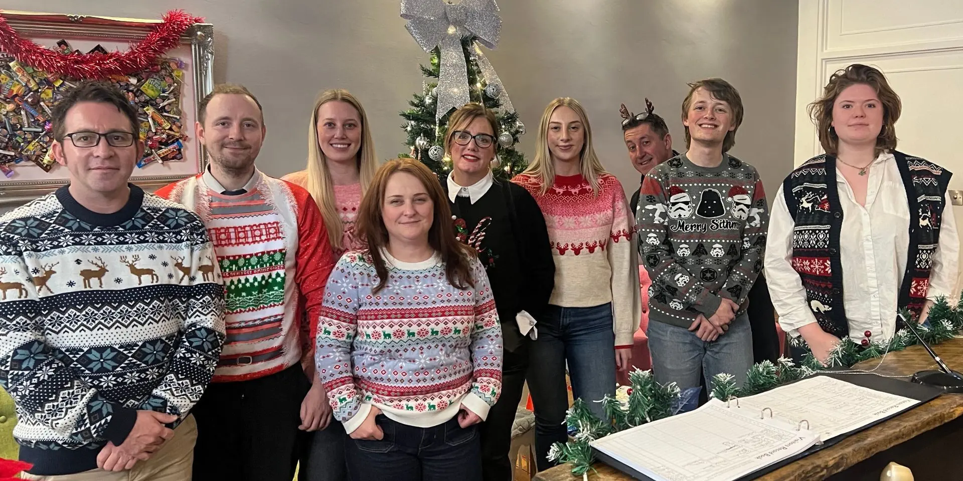 lexonik staff in Christmas jumpers, stood in front of a Christmas tree