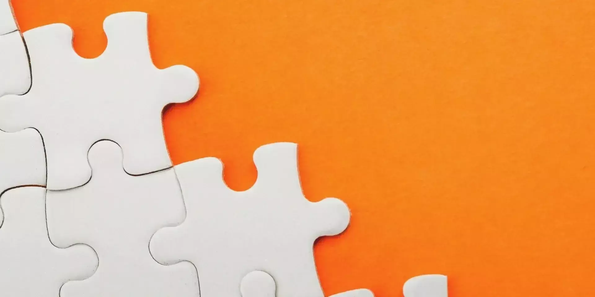 a white jigsaw being completed against an orange background