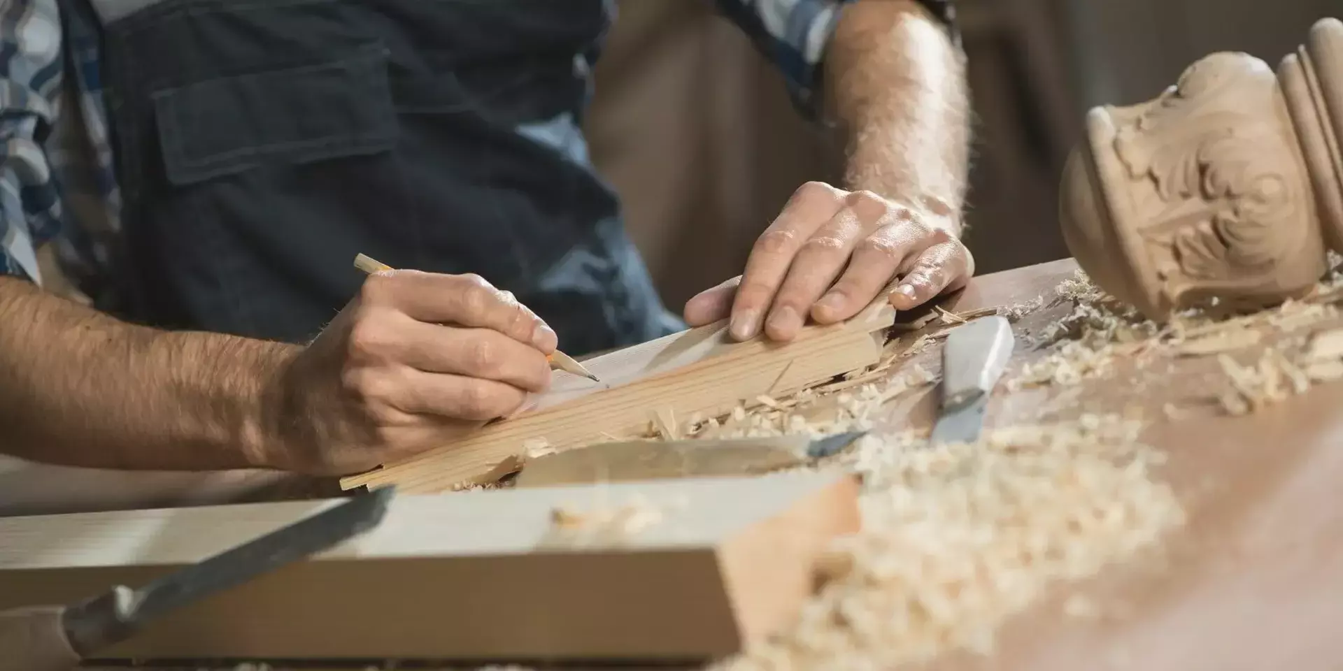 a craftsman whittling a piece of wood on a work bench