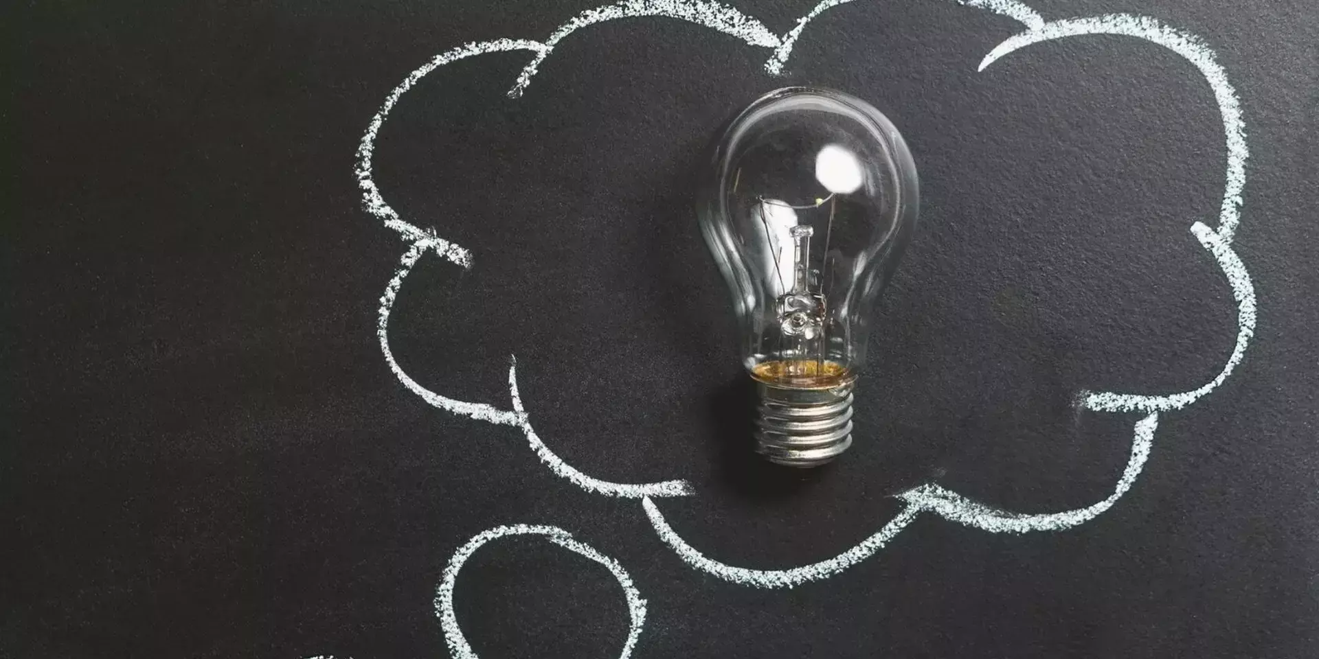 a light bulb on a blackboard with a chalk thought bubble around it