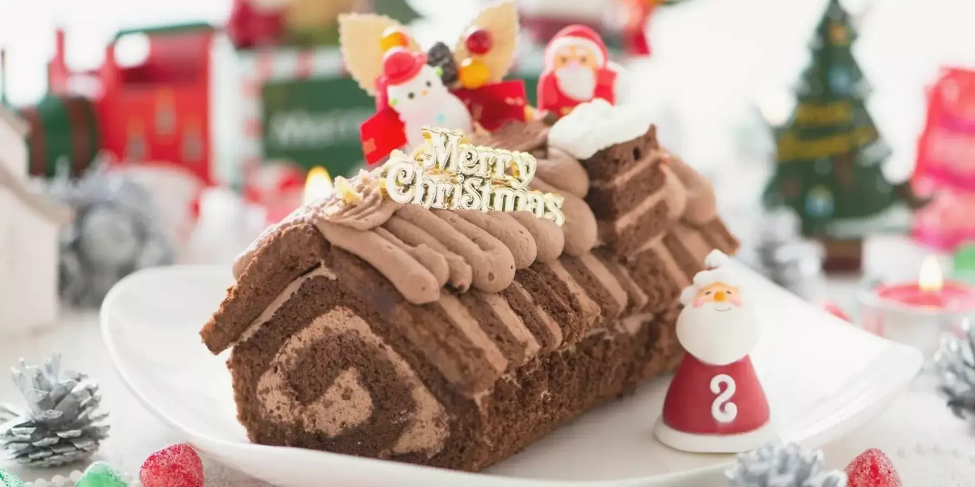 a yule log christmas dessert decorated with chocolate and santa clauses
