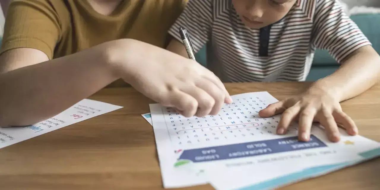 a child and an adult sat together doing a crossword