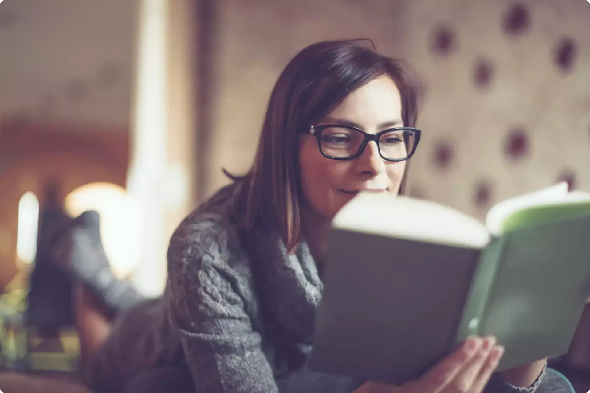 dark haired woman with glasses reading a book